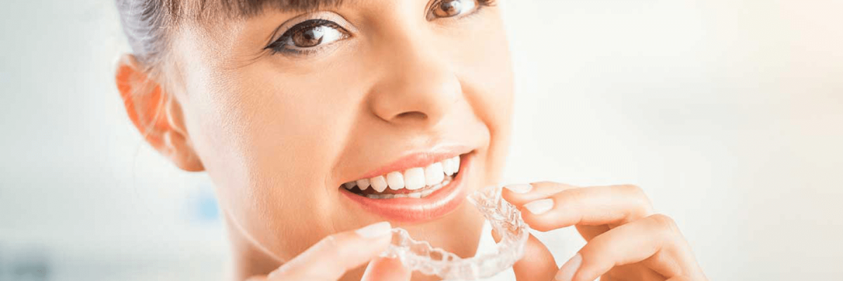 Woman holding Invisalign clear aligners